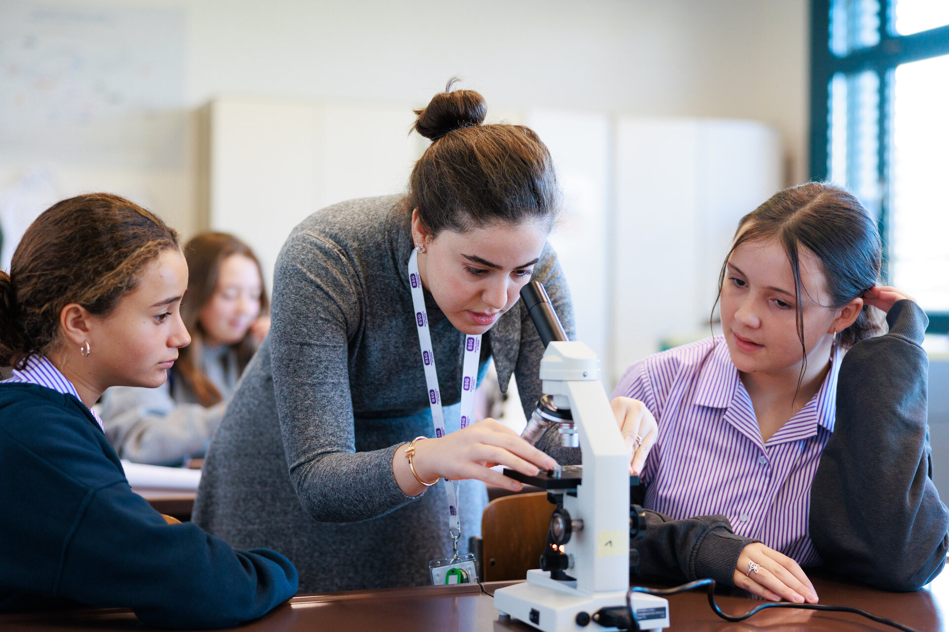 Teacher at the microscope with two students